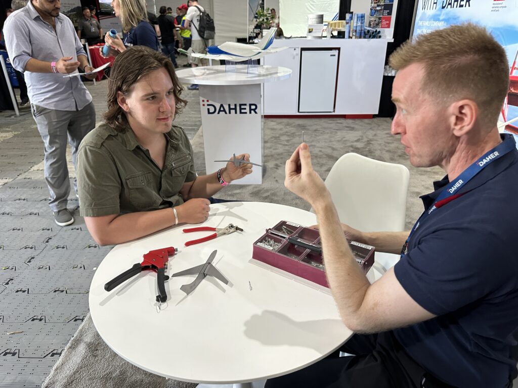 At the Daher booth in the Career Fair, we learn how to cleco a rivet. [Credit: Julie Boatman]