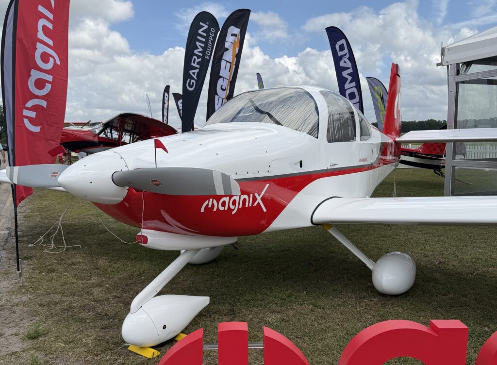 a van's RV-10 painted red and white with Magnix on the cowl and flags around it