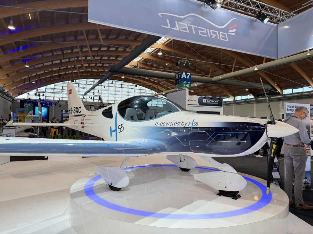 a white airplane with a digital gray and blue graphic on the cowl on a white platform
