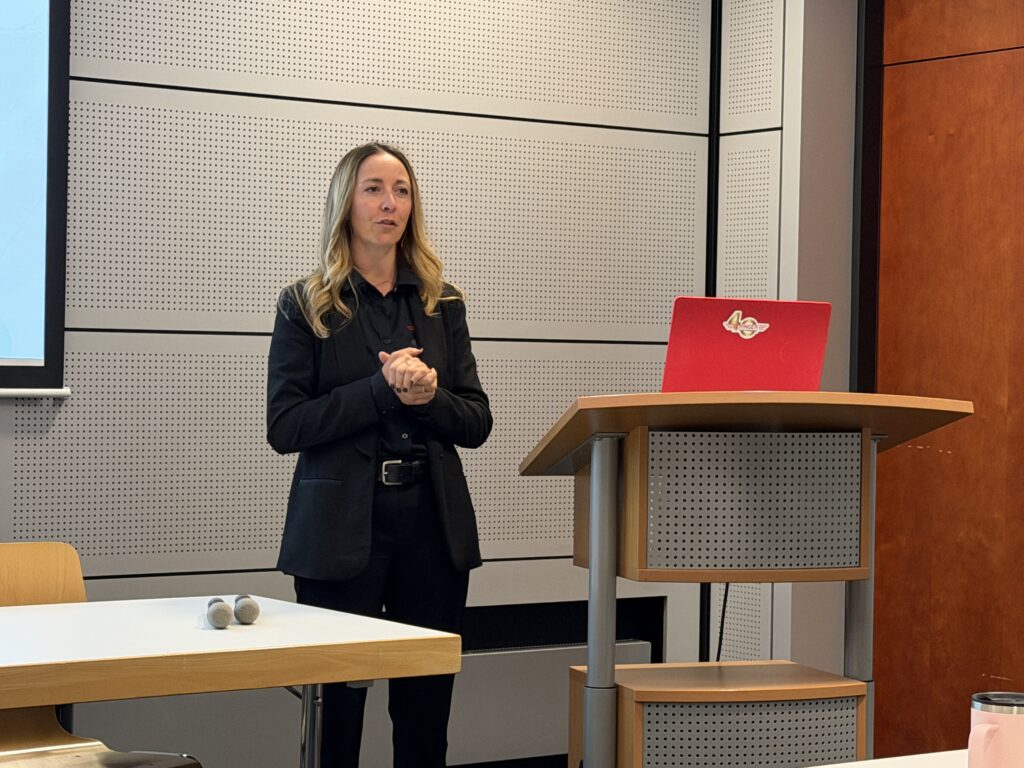 a woman stands next to a podium with a red laptop on it